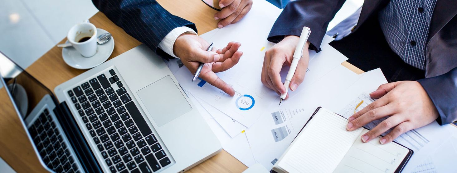 Zwei Mitarbeiter besprechen anhand von verschiedenen Dokumenten Finanzen